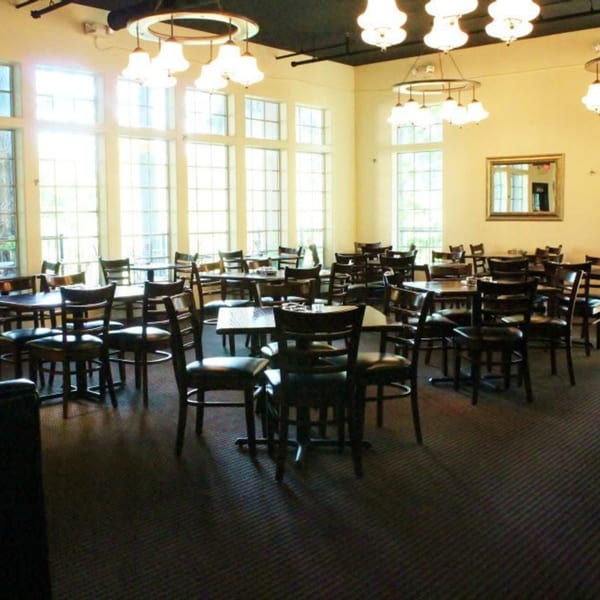 Dining room at Tree's Restaurant with many tables and chairs, large windows, and chandeliers.