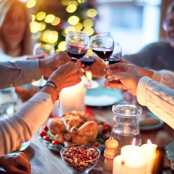 Hands clinking wine glasses over a southern dinner spread with roasted chicken and candles.