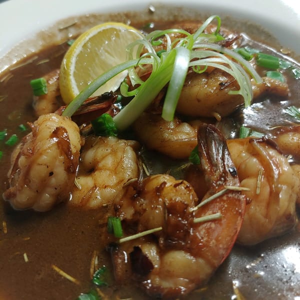 Southern-style shrimp in a rich brown sauce, garnished with a lemon slice and green onions.